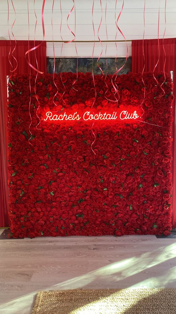 Rose red flower wall in Ajax with a neon sign that spells out "Rachel's Cocktail Club"