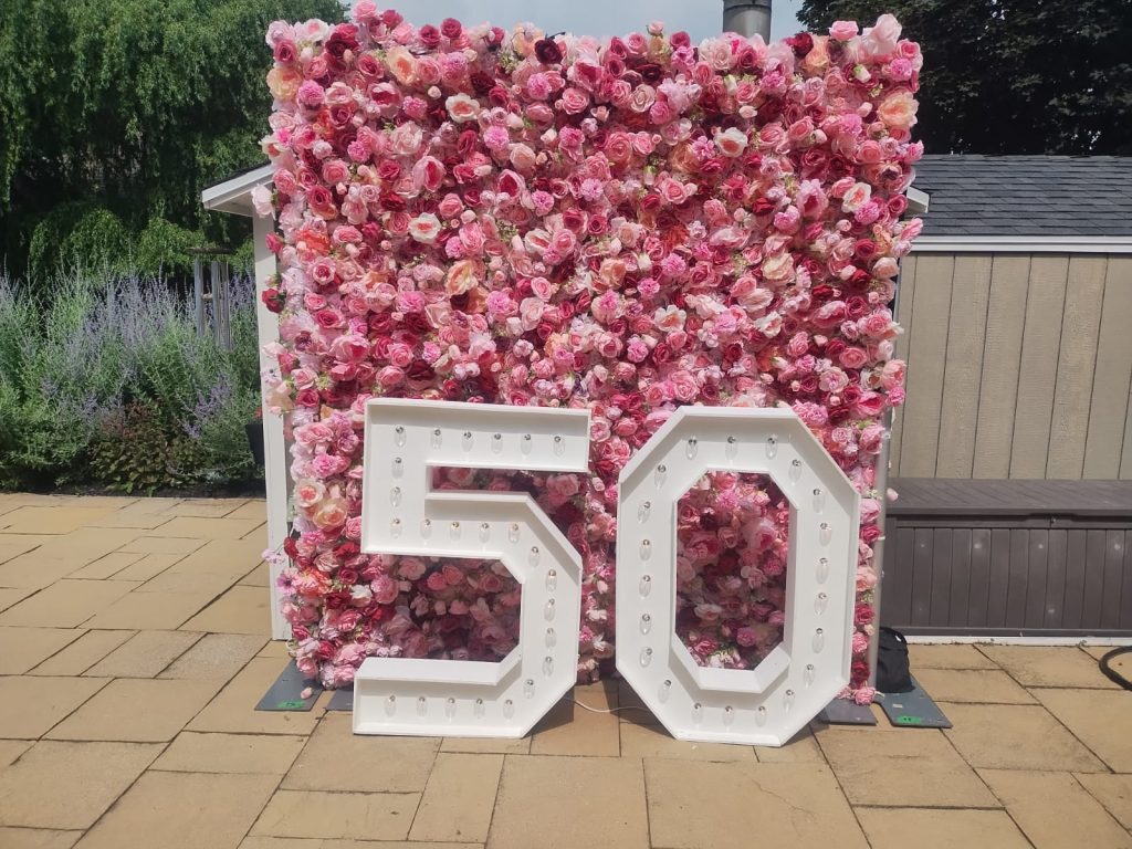 Pink Mississauga flower wall backdrop with marquee numbers that spell 50